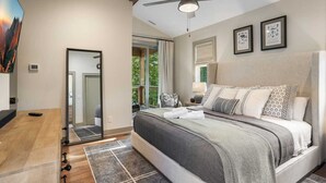 Une chambre moderne avec un grand lit, un ventilateur de plafond et une vue sur l’extérieur.