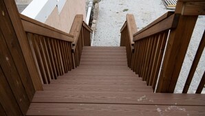 Una escalera de madera con barandilla que sube a un nivel superior.