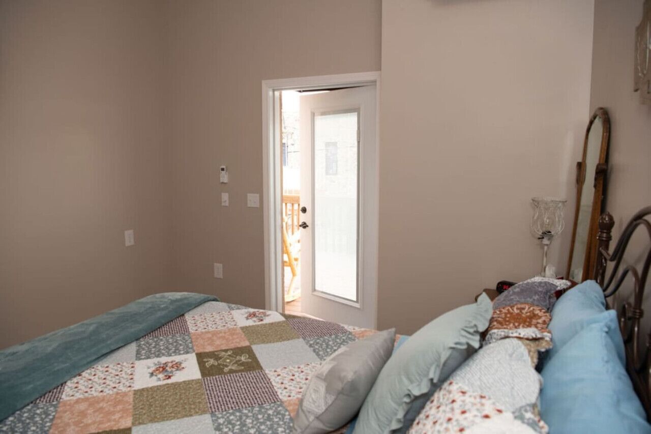 Un dormitorio con una colcha acolchada, cabecera de madera y puerta que da a un balcón.