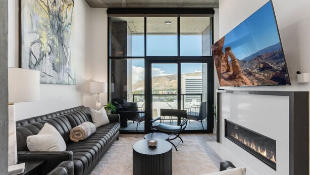 A modern living room with a black leather sofa, a round coffee table, and a fireplace. - Premium SLC Luxury- Penthouse VIEWS+ Top Amenities (Salt Lake City)