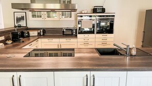 Eine moderne Küche mit Edelstahl-Dunstabzugshaube, eingebauter Mikrowelle, Toaster und einem Doppelbackofen.