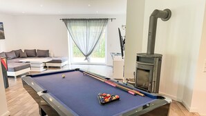 Ein Billardtisch mit Kugeln, eine Couch und ein Kamin im Wohnzimmer.