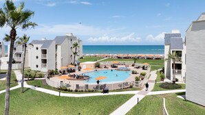 Un complexe hôtelier doté d’une piscine centrale, de parasols de plage et offrant une vue sur l’océan.