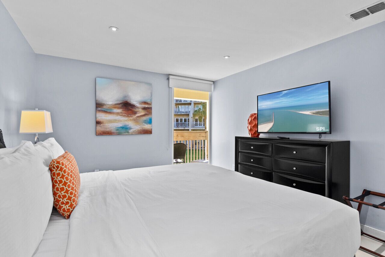 Une chambre d’hôtel moderne dotée d’un grand lit, d’un téléviseur à écran plat, d’un tableau et donnant sur le balcon extérieur.