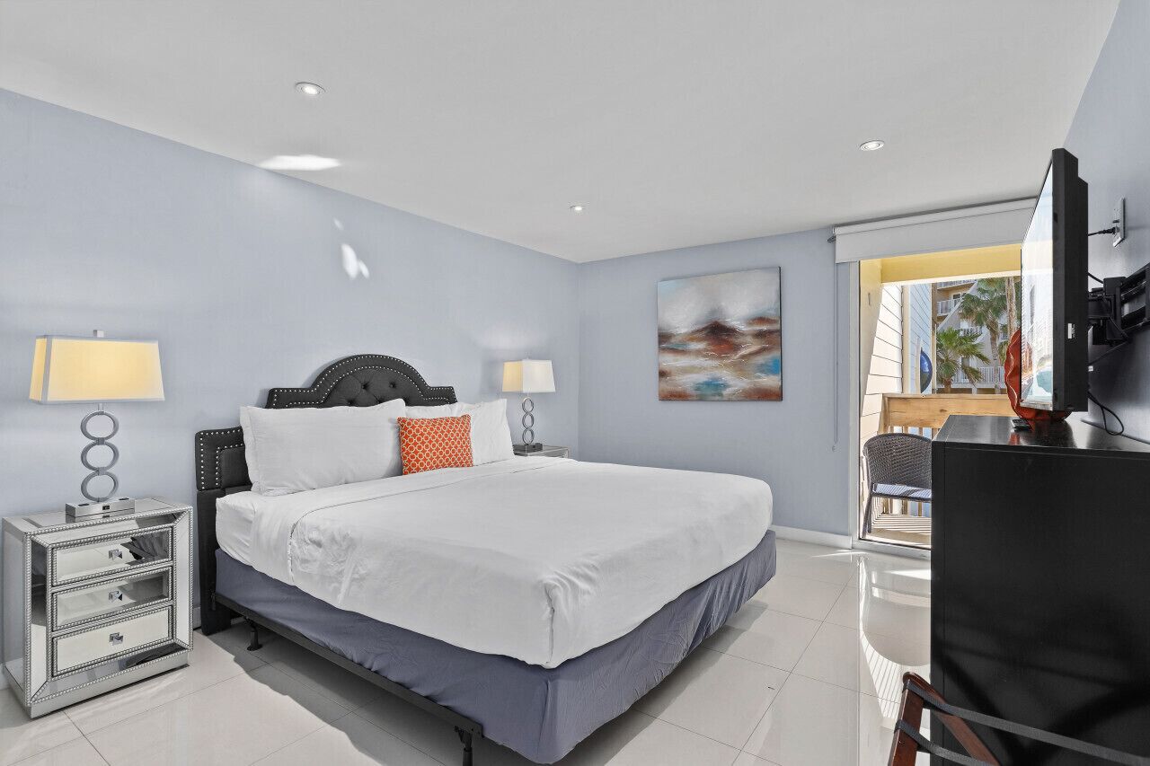Une chambre d’hôtel moderne dotée d’un grand lit, de tables de chevet, d’un téléviseur à écran plat et offrant une vue sur l’extérieur.