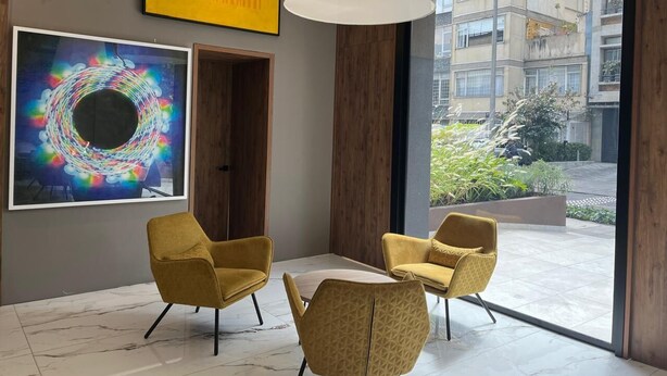 A modern interior with a large window, two yellow chairs, and artwork on the wall. - Art Homes 85 (Bogotá)