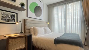 A modern hotel room with a large bed, a desk with a lamp, and artwork on the walls. - Art Homes 85 (Bogotá)