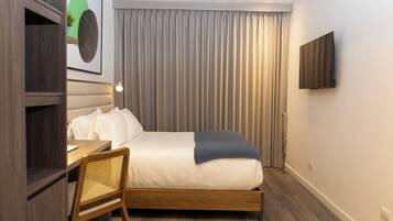 Quarto de hotel moderno com cama de madeira, uma escrivaninha e uma cadeira.
