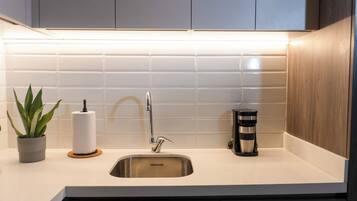 Una cocina moderna con un lavamanos de acero inoxidable, una cafetera y una planta en maceta.