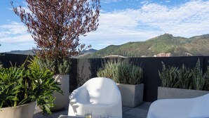 A rooftop terrace with a table set for two, surrounded by potted plants and white chairs, overlooking a mountainous landscape. - Art Homes 85 (Bogotá)