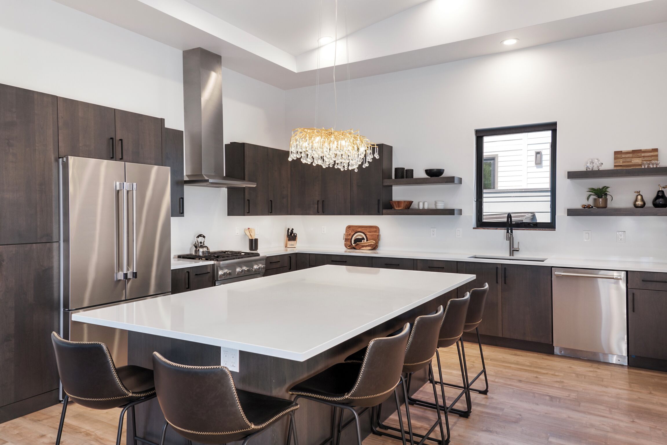 A modern kitchen with a large island, stainless steel appliances, and dark wood cabinetry.