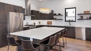 A modern kitchen with a large island, stainless steel appliances, and dark wood cabinetry.