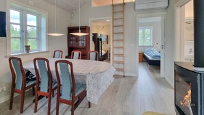 Ein Essbereich mit einem runden Tisch, Stühlen und einer Deckenleuchte. Im Hintergrund befindet sich ein Holzschrank und eine Leiter.