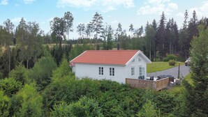 Ein weißes Haus mit rotem Dach, umgeben von dichtem Wald.