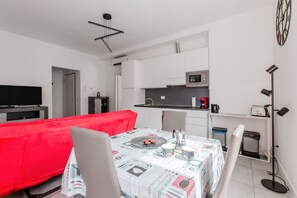 Apartamento moderno com área de jantar, cozinha compacta e televisão.
