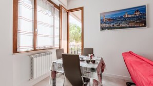 A dining area with a table set for two, a red bench, and a cityscape painting on the wall. - GuestHost - Modern 75 sqm apartment, able to comfortably accommodate up to 4 people, located on the second floor of a building with lift (a few steps to reach the lift). The property is located in the San Jacopino area, a lively neighborhood well connect (Firenze)