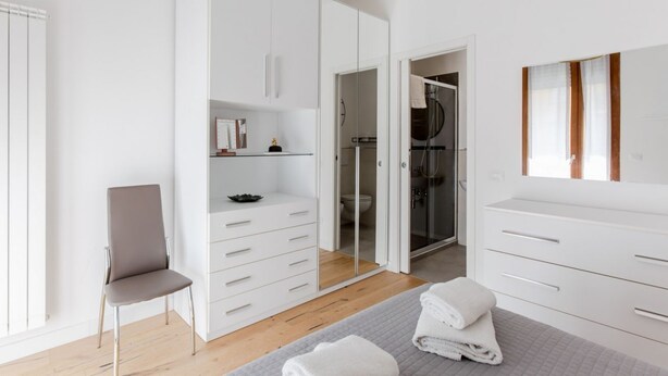 A modern bedroom with a bed, a chair, a wardrobe, and a walk-in closet. - GuestHost - Modern 75 sqm apartment, able to comfortably accommodate up to 4 people, located on the second floor of a building with lift (a few steps to reach the lift). The property is located in the San Jacopino area, a lively neighborhood well connect (Firenze)