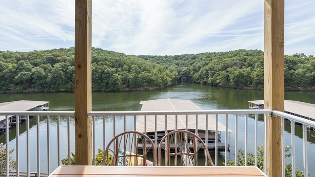 A wooden deck with a view of a river and forest. - Lazy Days E-08 - Two Bedroom Apartment, Sleeps 6 (Osage Beach)