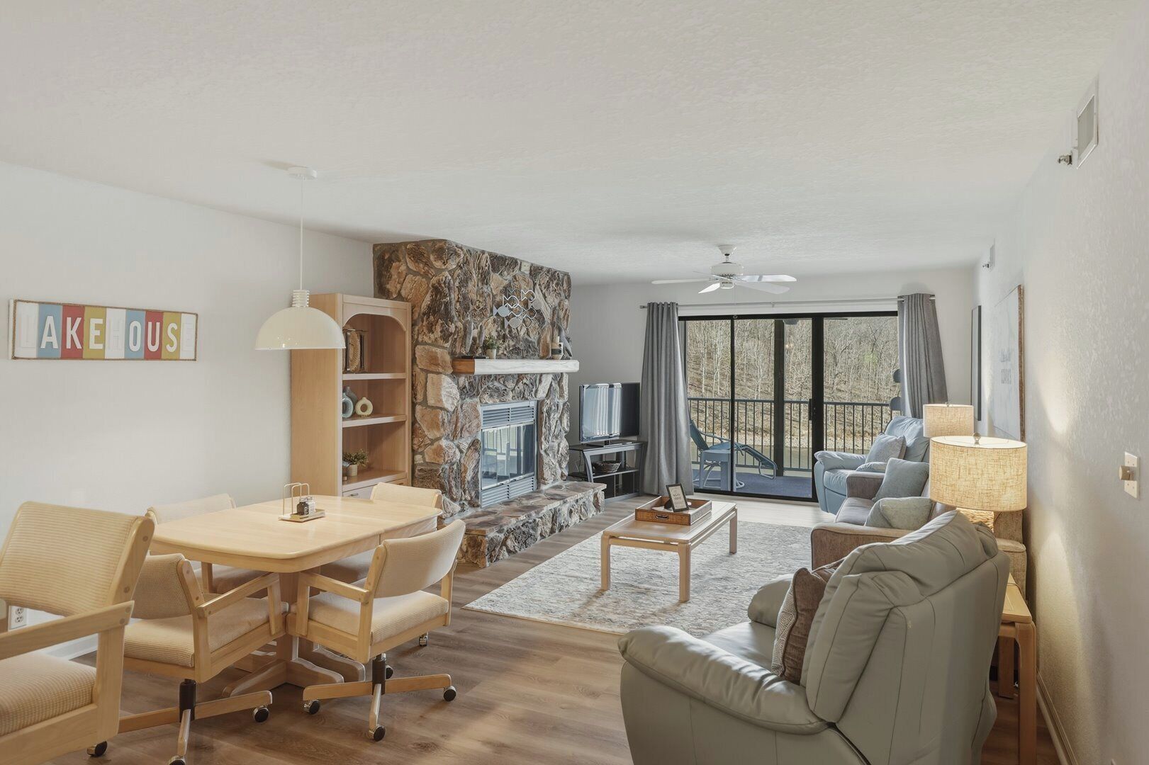 A living room with a stone fireplace, a dining area, and a sofa.