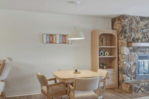 Ein Essbereich mit Tisch und Stühlen, einer Hängelampe, einem Bücherregal und einer Steinwand.