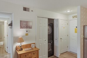 A laundry room with a washer and dryer, a lamp, a sign reading 'Lake Life,' and a door leading to another room. - Lazy Days E-08 - Two Bedroom Apartment, Sleeps 6 (Osage Beach)