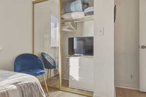 A bedroom with a bed, a blue chair, a wardrobe, and a television. - Lazy Days E-08 - Two Bedroom Apartment, Sleeps 6 (Osage Beach)