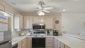 A kitchen with light wood cabinets, stainless steel appliances, a ceiling fan, and a clock on the wall. - Lazy Days E-08 - Two Bedroom Apartment, Sleeps 6 (Osage Beach)