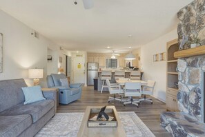 A modern living room with a sofa, a coffee table, and a dining area with chairs and a table.