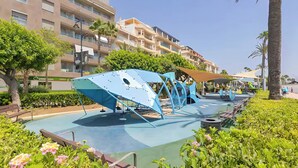 Un hotel moderno con zona de piscina que presenta una estructura azul distintiva y palmeras.