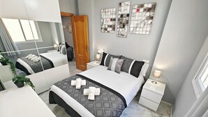 Una habitación de hotel moderna con una cama grande, una mesita de noche, un espejo y una puerta.