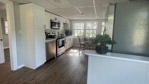 A modern kitchen with white cabinetry, stainless steel appliances, and a dining area with a wooden table and chairs.