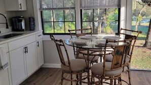 A kitchen with white cabinets, a coffee maker, and a window with blinds.