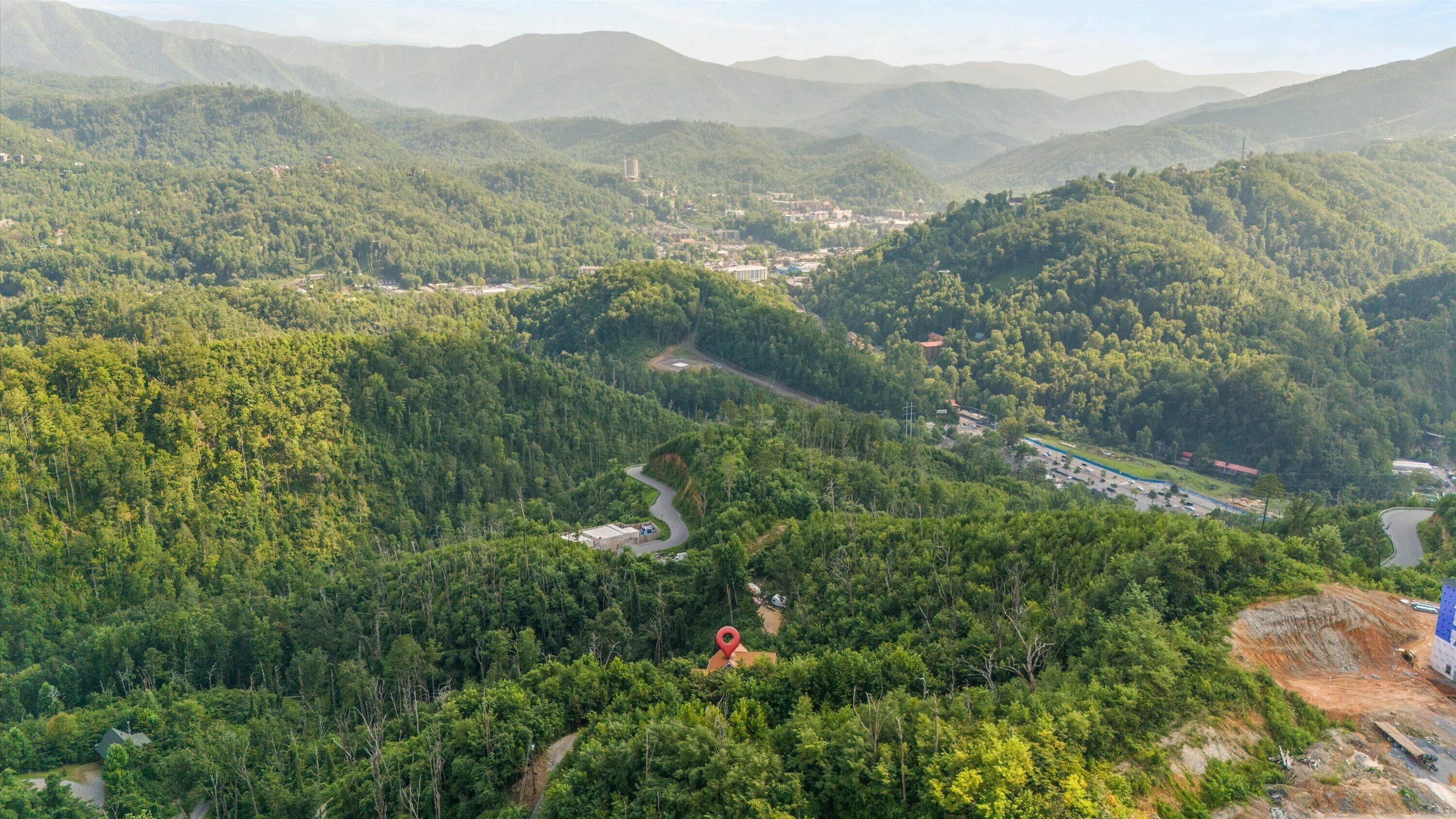 A mountainous landscape with dense forests, winding roads, and scattered buildings.