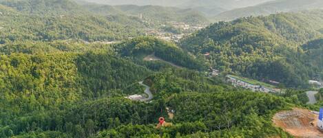 A mountainous landscape with dense forests, winding roads, and scattered buildings.