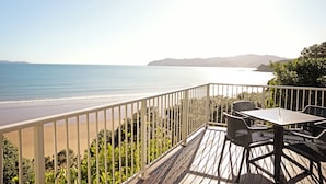 Una terraza con mesa y sillas que da a una playa con cielos despejados.