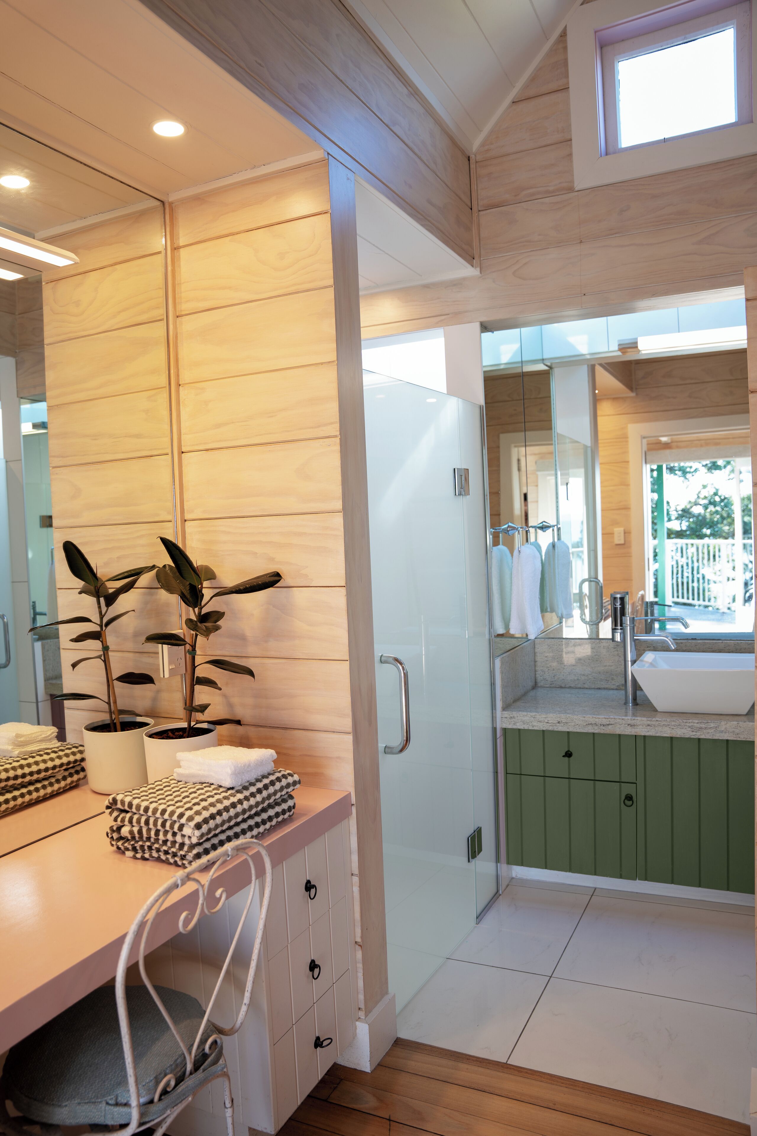 A modern bathroom with a wooden ceiling, a large mirror, a sink, and a green cabinet.