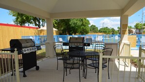 Un patio al aire libre con una parrilla y sillas de metal.