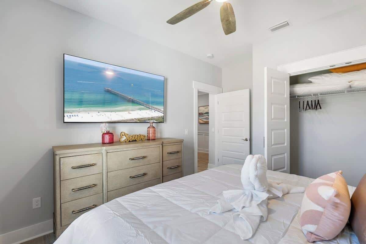 Ein Schlafzimmer mit einem Bett, einer Kommode, einem an der Wand befestigten Fernseher und einem Kleiderschrank.