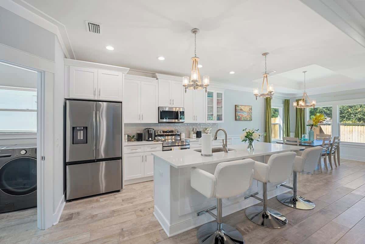 A modern kitchen with stainless steel appliances, a central island with bar stools, and pendant lighting.
