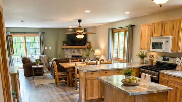 Una cocina amplia con armarios de madera, una isla central y un comedor con sofá y sillas.