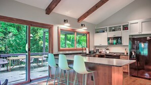 Una cocina moderna con una isla grande, taburetes de bar y vistas al exterior.