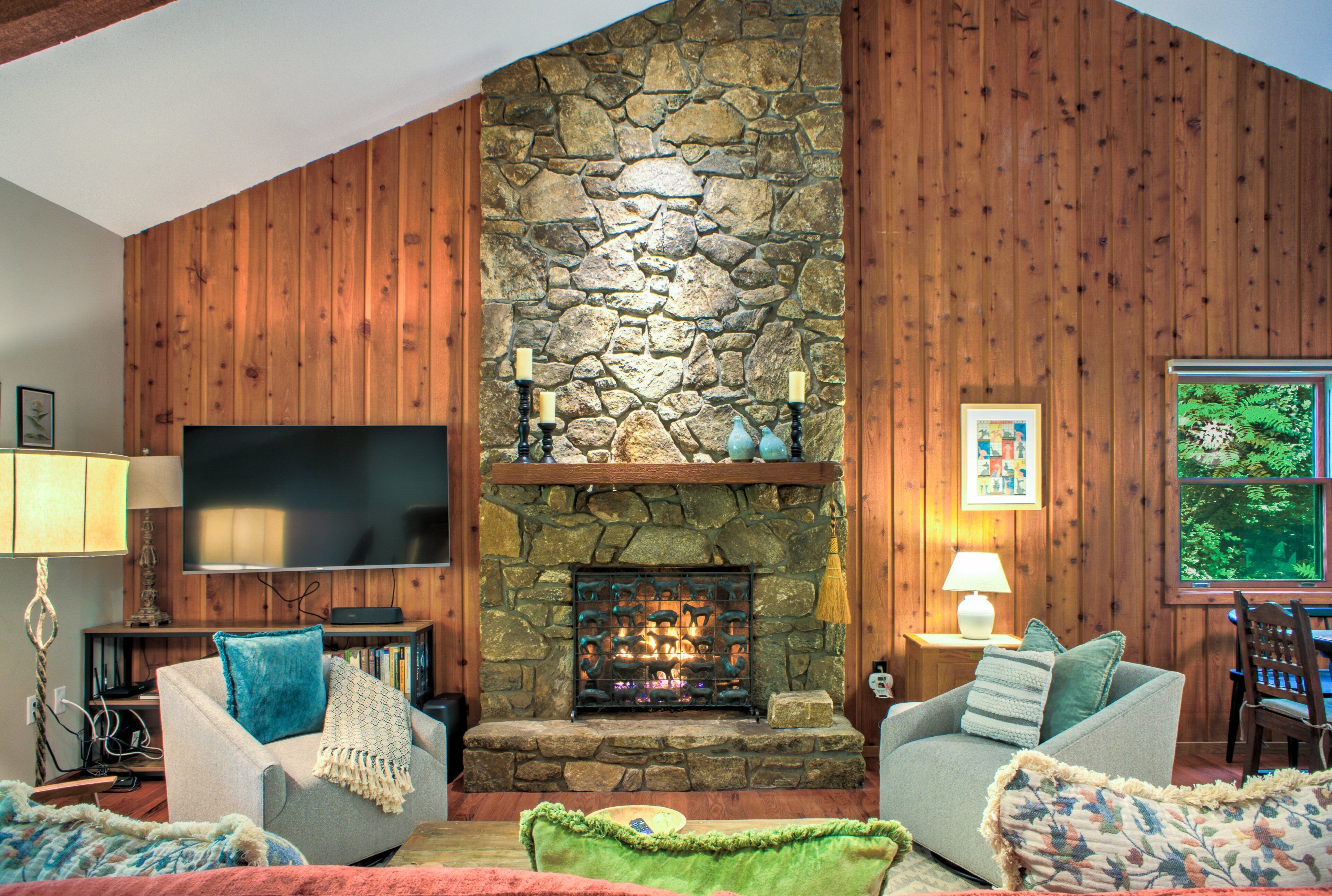 Un salon chaleureux avec une cheminée en pierre, des murs en bois, un téléviseur à écran plat et des sièges confortables.