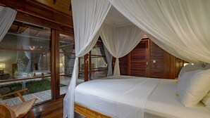 A bedroom with a canopy bed, wooden flooring, and large windows. - Villa Lou Ann (Canggu)