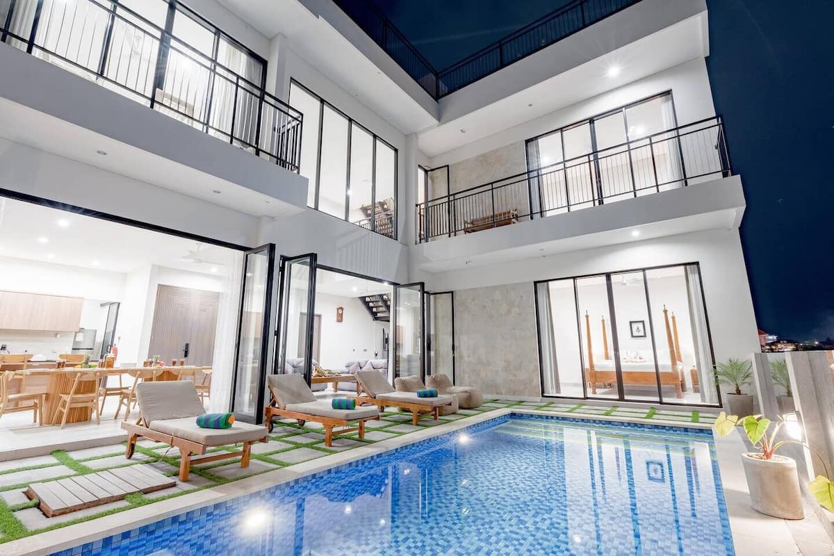 A multi-level modern home with a central swimming pool, balconies, and a dining area.