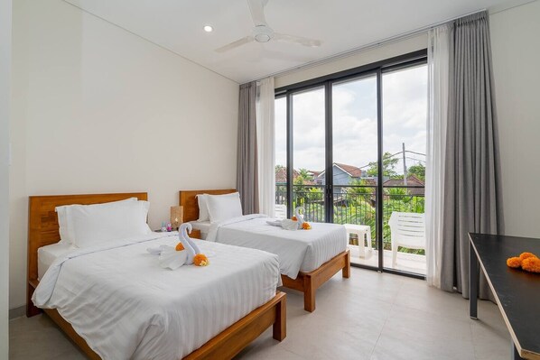 A hotel room with two beds, a balcony, and a view of the neighborhood. - Zen Villa - Central Canggu (Canggu)