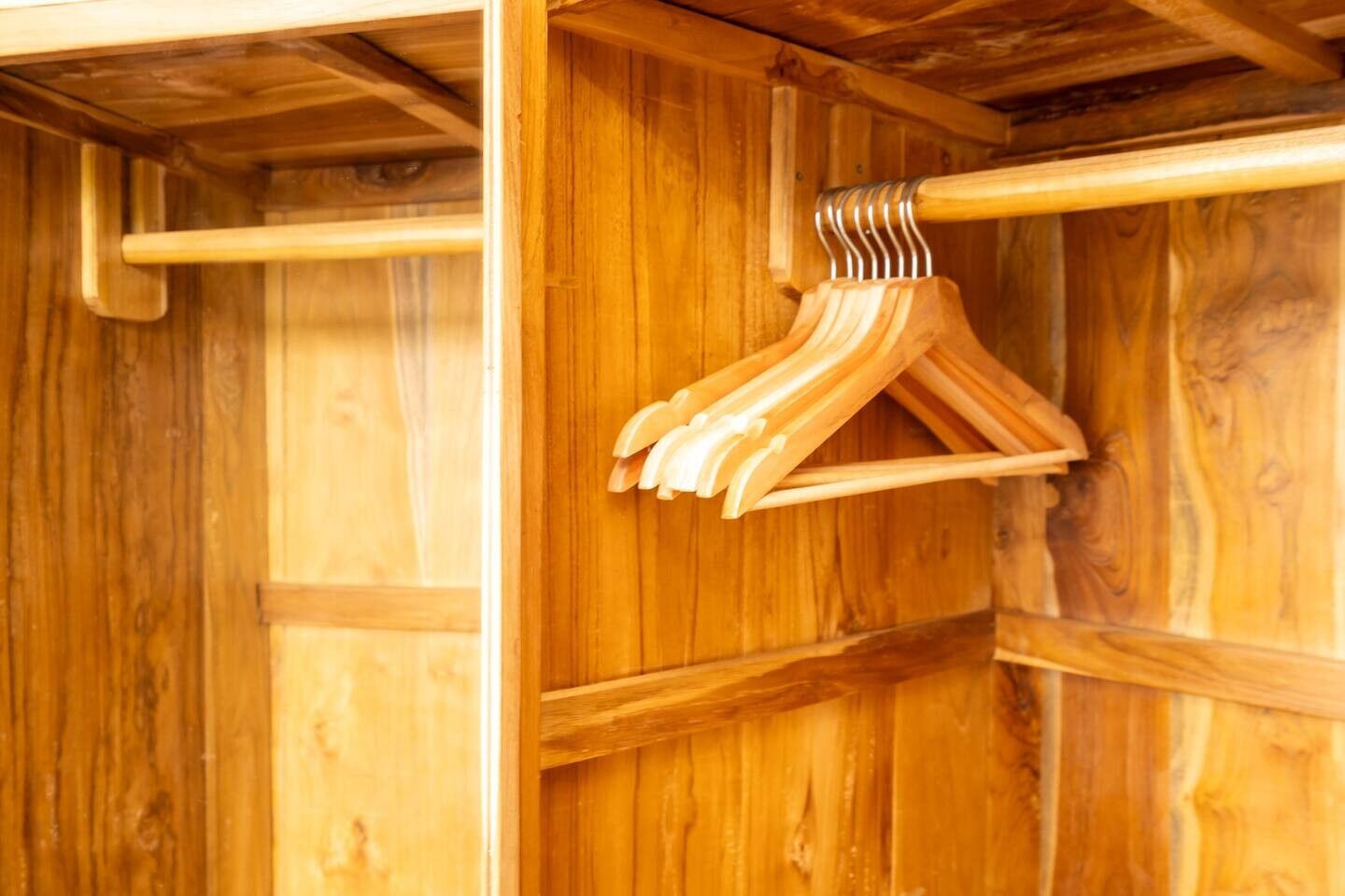 A wooden wardrobe with multiple wooden hangers.