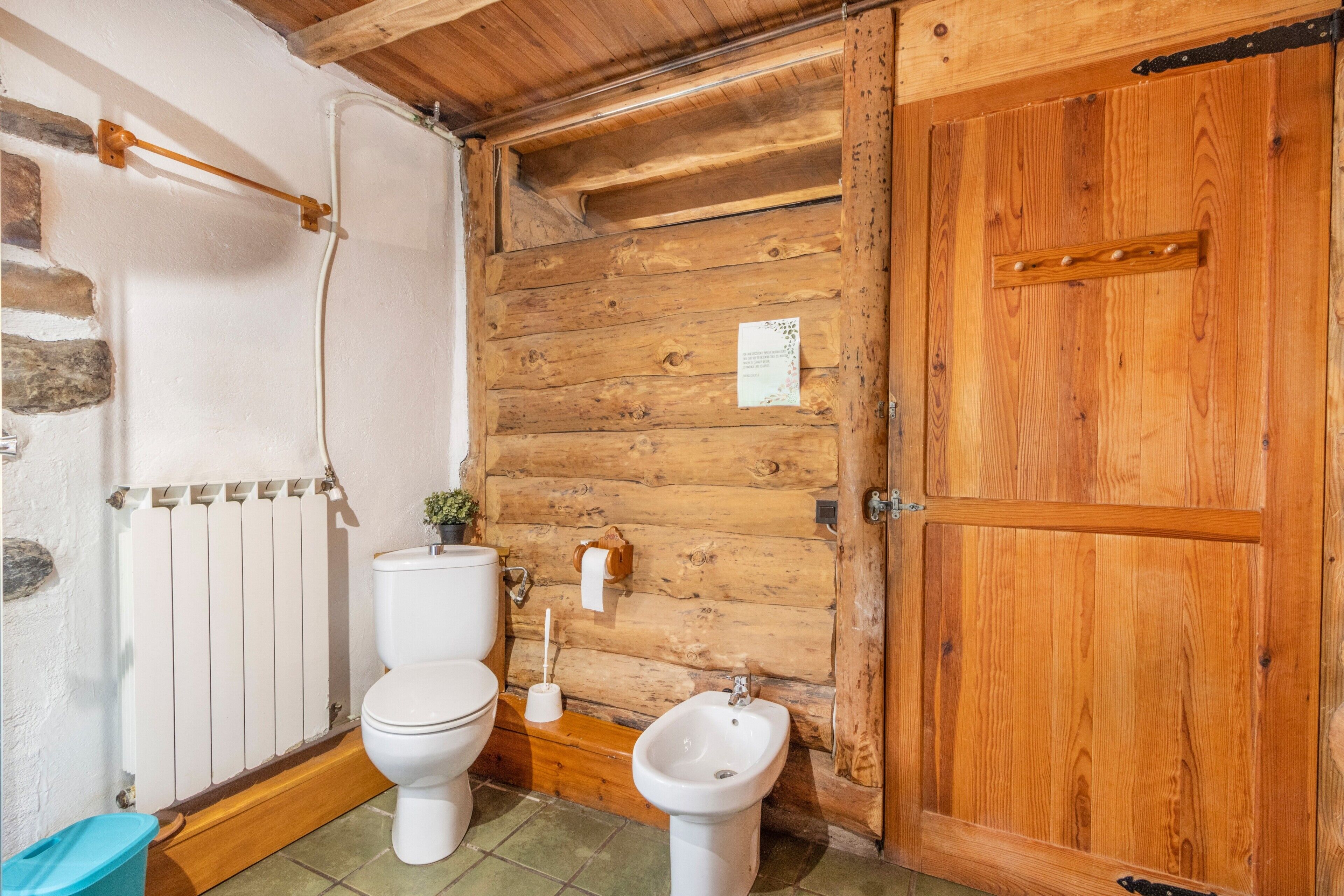 A wooden cabin bathroom with a toilet, bidet, and wooden walls.