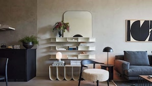 A modern living room with a sofa, a side table, a lamp, and a decorative mirror.