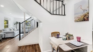 A modern living room with a grey sofa, a coffee table, and a staircase with black railings. - Experience paradise! Three bedrooms in Fort Myers Beach accommodation up to 10+  (Fort Myers Beach)