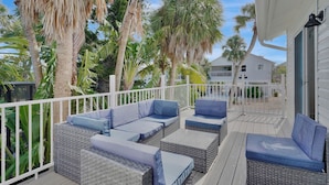 A covered outdoor deck with wicker furniture and a white railing. - Experience paradise! Three bedrooms in Fort Myers Beach accommodation up to 10+  (Fort Myers Beach)